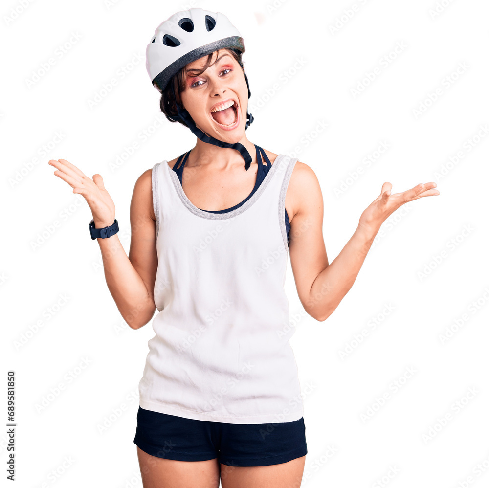Beautiful young woman with short hair wearing bike helmet celebrating victory with happy smile and winner expression with raised hands Beautiful young woman with short hair wearing bike helmet celebrating victory with happy smile and winner expression with raised hands