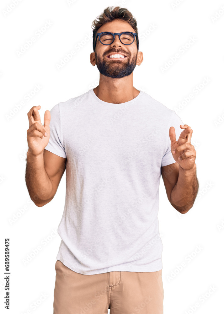 Naklejka premium Young hispanic man wearing casual clothes and glasses gesturing finger crossed smiling with hope and eyes closed. luck and superstitious concept.