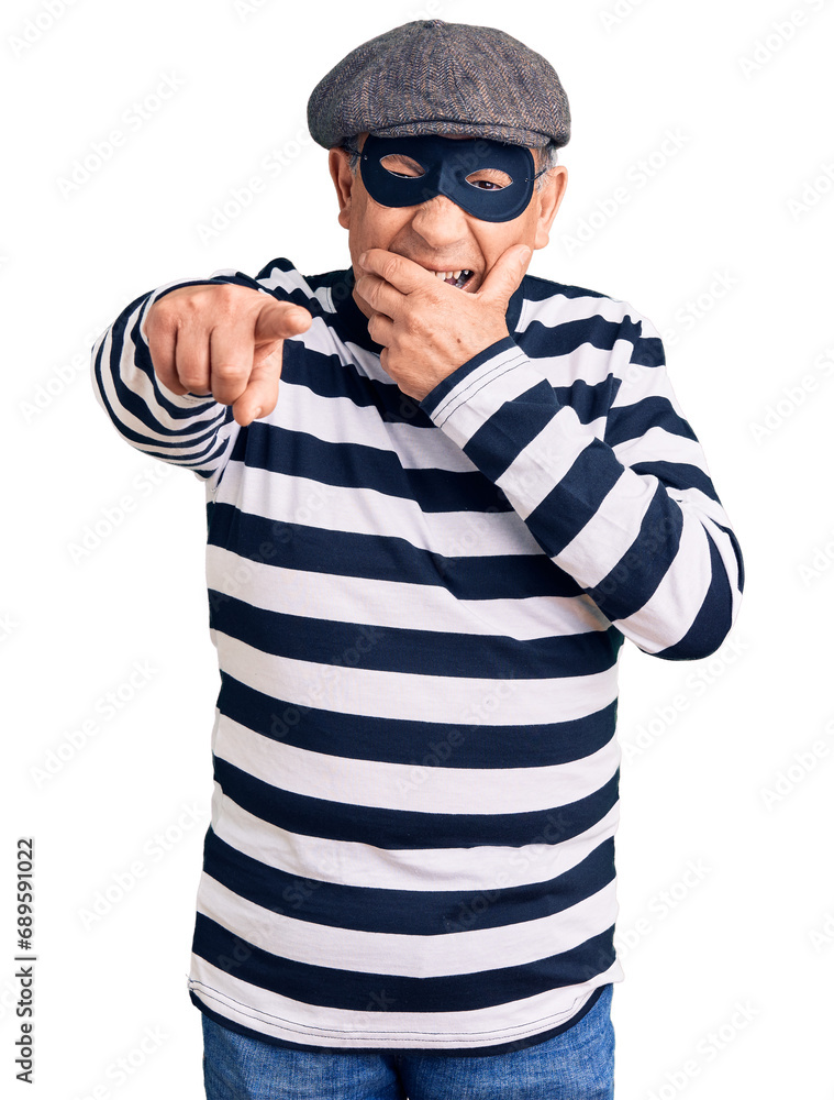 Senior handsome man wearing burglar mask and t-shirt laughing at you, pointing finger to the camera with hand over mouth, shame expression Senior handsome man wearing burglar mask and t-shirt laughing at you, pointing finger to the camera with hand over mouth, shame expression