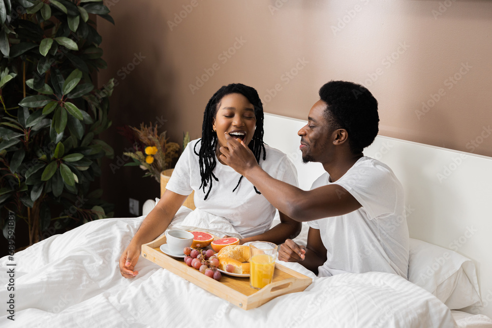 Beautiful African American couple in love sitting in bed drinking ...