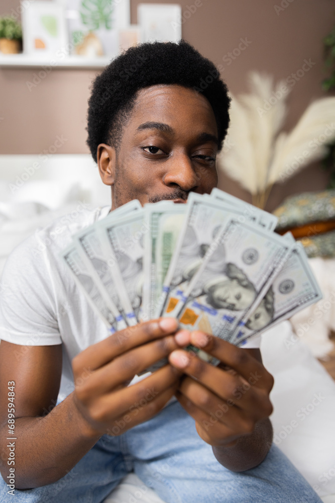 Handsome afr american dark skinned man holding money cash dollars in hands showing at camera high salary concept. Handsome afr american dark skinned man holding money cash dollars in hands showing at camera high salary concept.