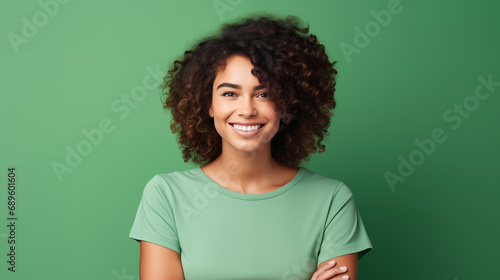 Beautiful black woman wearing a green t-shirt  smiling and looking at the camera on a plain green background