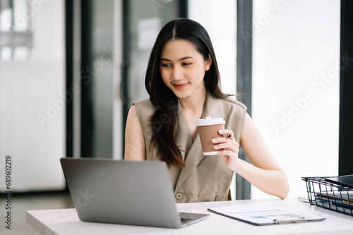 Asian Businesswoman Analyzing Finance on Tablet and Laptop at modern Office Desk tax  report 