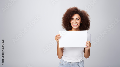 Black woman holding a blank sign and smiling on a plain  birght background photo