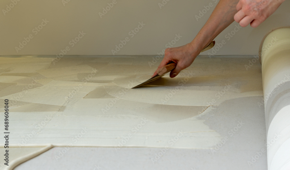Αυτοκόλλητο Man prepares the floor with glue for a new carpet.