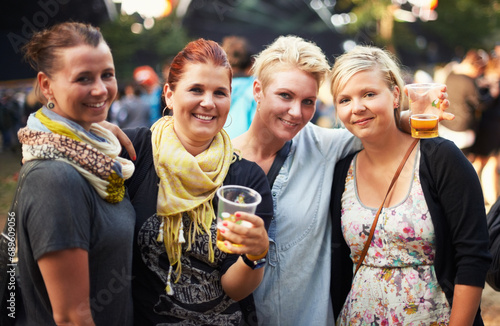 Portrait of group of women at music festival with beer, smile and hug in nature together. Drink, celebration and friends relax at outdoor party with freedom, adventure and happy people at concert.