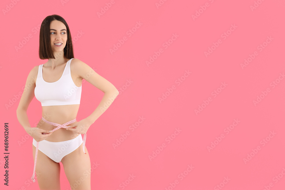 A slim girl in underwear measures her waist. - obrazy, fototapety, plakaty 