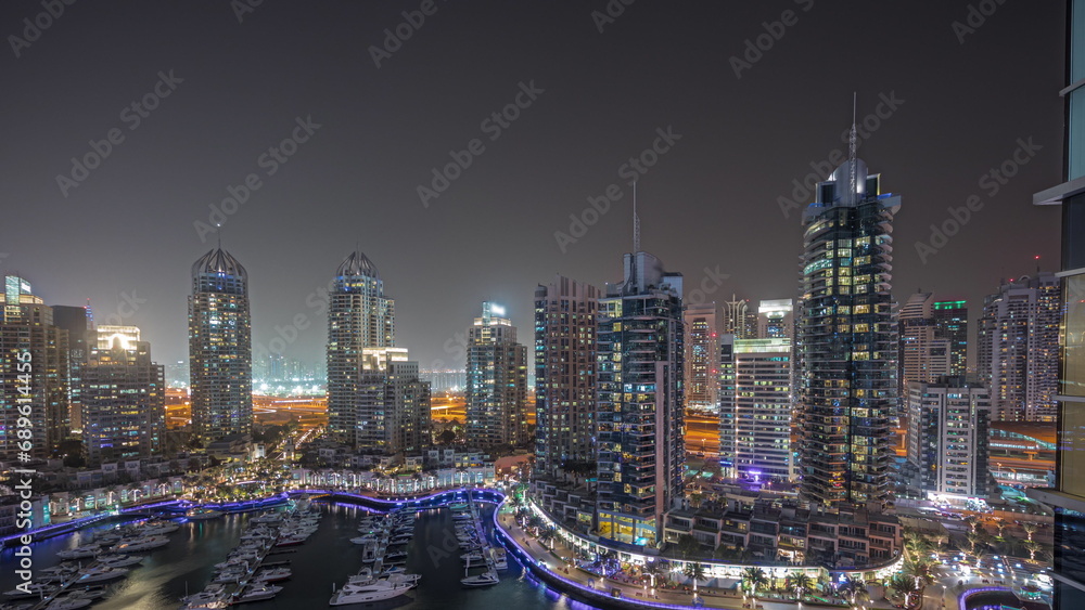 Fototapeta premium Panorama showing Dubai marina tallest skyscrapers and yachts in harbor aerial night timelapse.