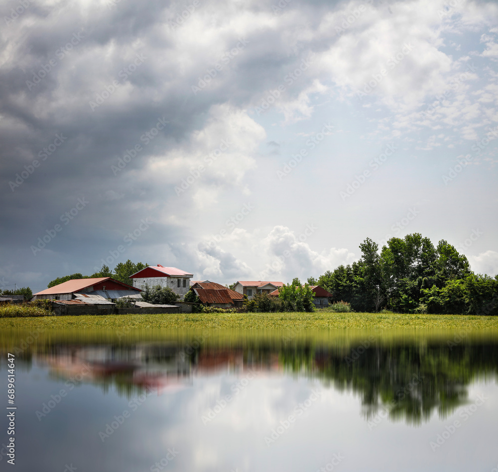 A view of a village and a beautiful pond in the village. Old buildings, shady forest and a small lake. View of the village. Farm. A view of a village and a beautiful pond in the village. Old buildings, shady forest and a small lake. View of the village. Farm.