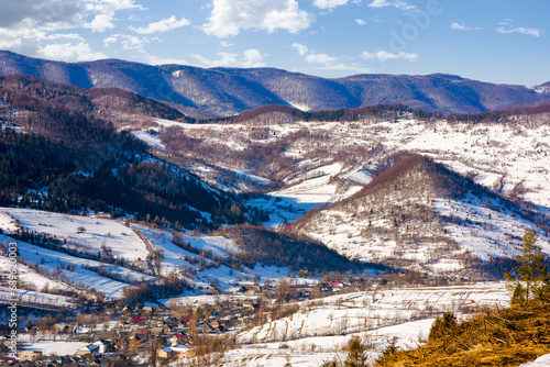 mountainous rural landscape in winter. countryside scenery with village in the valley. sunny weather