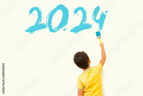 Cute little boy drawing new year 2024 with painting brush on wall background
