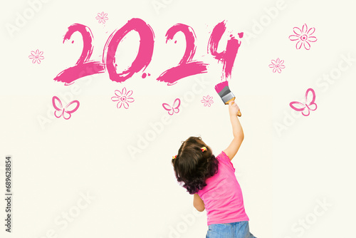 Cute little girl drawing new year 2024 with painting brush on wall background