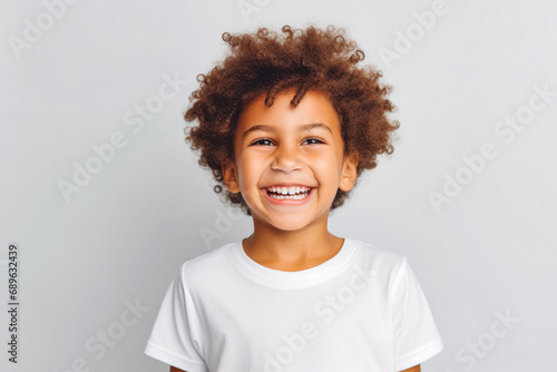 Cute mixed race boy child model with perfect clean teeth laughing and smiling, happy. Curly hair and white shirt, healthy. Isolated on white background. photo