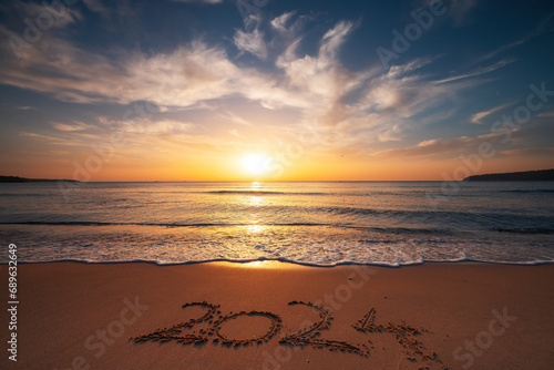 Happy New Year 2024 concept  lettering on the beach. Written text on the sea beach at sunrise.