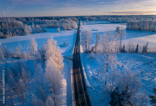 Winter Wonderland Sunrise: Majestic Aerial View of a Swedish Landscape with a Serene Roadway Cutting Through the Frozen Beauty (ID: 689635874)