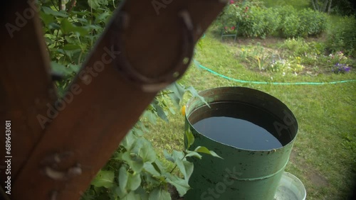 Rustic garden supplies: water barrel ready for watering, garden hose in background