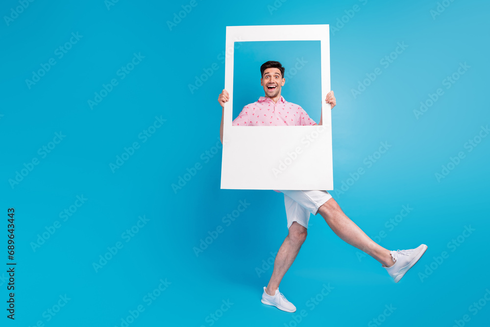Full size photo of overjoyed cheerful person hold paper album card dancing isolated on blue color background Full size photo of overjoyed cheerful person hold paper album card dancing isolated on blue color background