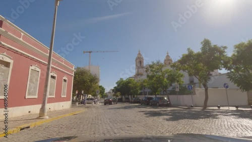 First person view, FPV, from dashcam of car driving downtown through the historic center of Faro, Algarve Coast, Portugal. Road trip video in POV, with blue sky