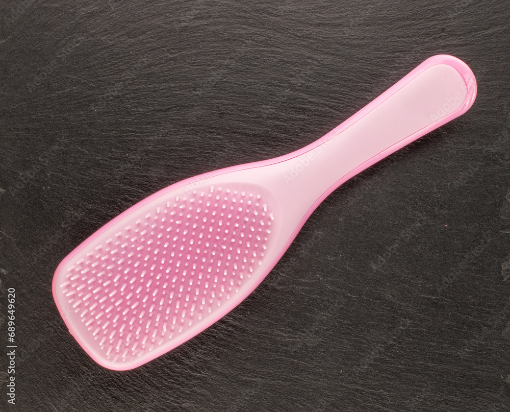 One pink plastic hairbrush on slate stone, macro, top view. One pink plastic hairbrush on slate stone, macro, top view.
