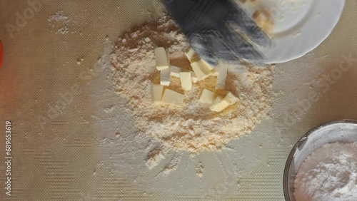 Adding butter to a mixture of flour and egg to make shortbread. The process of making shortbread on a silicone mat