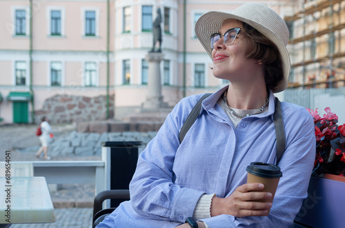 A girl drinks coffee from a paper cup in a coffee shop on the street of an ancient city