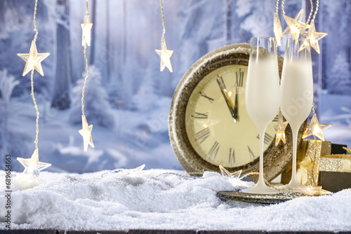 Big new year closk on table and free space for your products. Blurred background of landscape and snow flakes with frost. Mockup backdrop of december time at night. photo