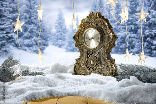 Big new year closk on table and free space for your products. Blurred background of landscape and snow flakes with frost. Mockup backdrop of december time at night. photo