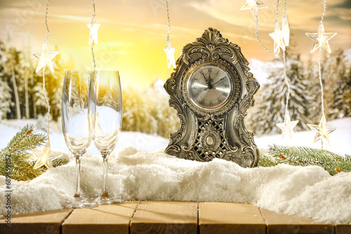 Big new year closk on table and free space for your products. Blurred background of landscape and snow flakes with frost. Mockup backdrop of december time at night.  photo