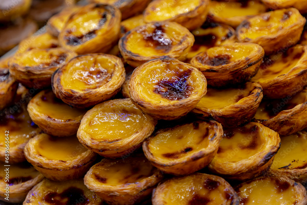 Stack of Portuguese egg tart (Pasteis de Nata) display in front of shop, A delicious local favourite dessert with pastry shell, Sweet tarts with an aromatic custard that gets baked and scorched on top