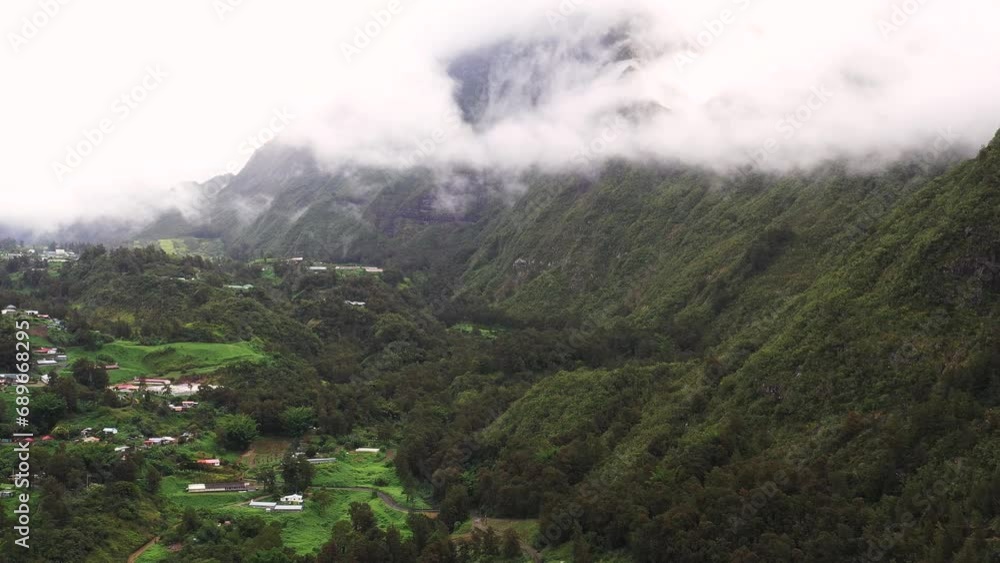Panoramic aerial drone view of Cirque de Salazie with Piton d'Anchaing and a creole village on a plateau on a rainy day, Saint Andre, Reunion. Panoramic aerial drone view of Cirque de Salazie with Piton d'Anchaing and a creole village on a plateau on a rainy day, Saint Andre, Reunion.