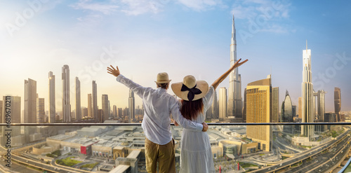 A happy tourist couple on vacation time stands on a balcony and enjoys the panoramic view of the Dubai city skyline, UAE