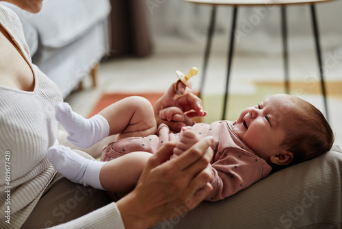Tableau sur toile Side view of smiling newborn lying on moms knees and looking at mother, copy spa