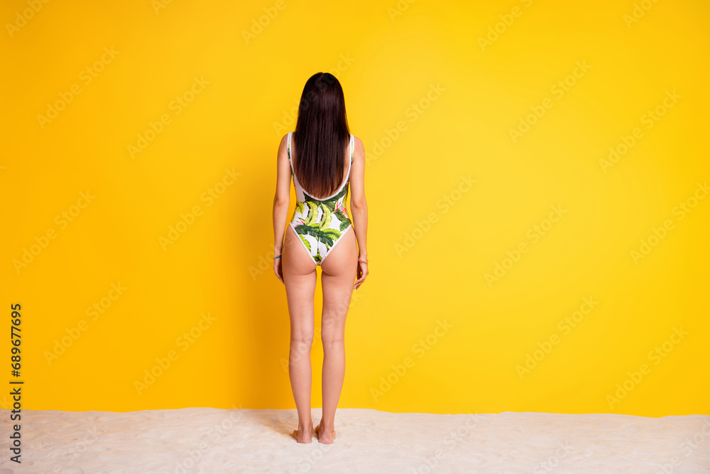 Full length photo of slim sexy lady wear bikini standing back sand beach empty space isolated yellow color background - obrazy, fototapety, plakaty 