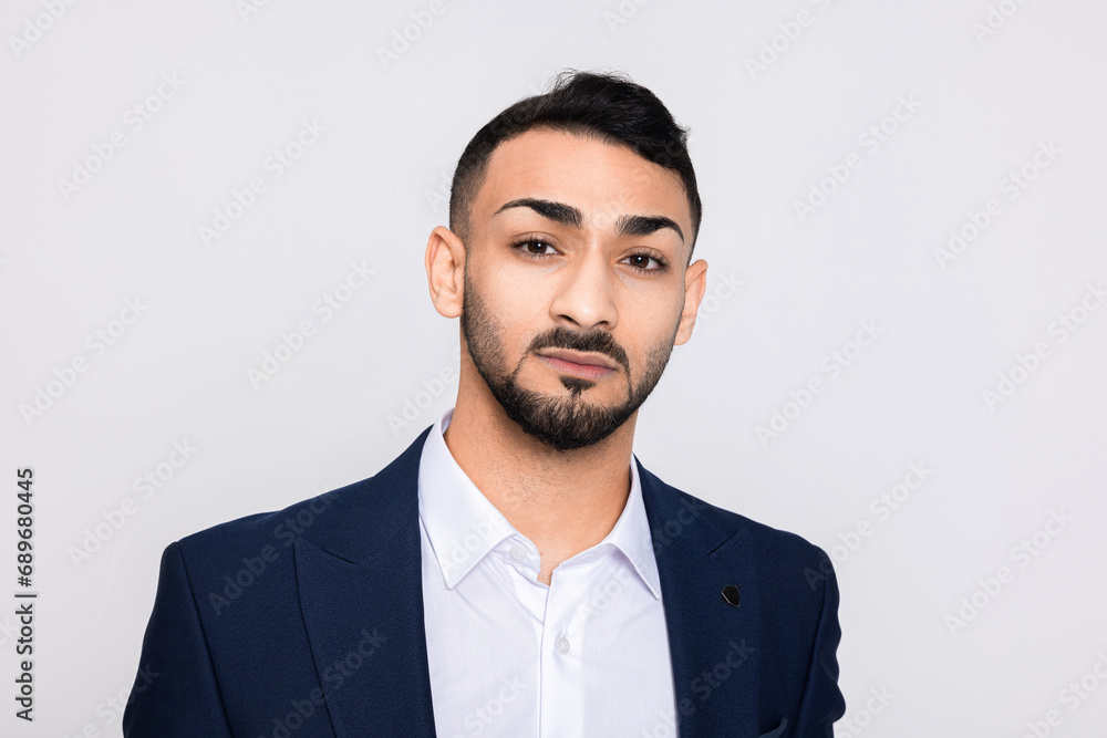 Serious concentrated middle eastern young man wearing ellegant suit and white shirt looking at camera close up shot on serious emotions.