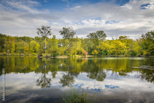 Scenic autumn lake with calm waters and mirror like reflection in the water and a blue sky with white clouds