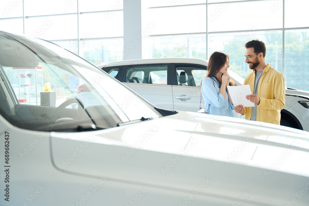 Joyful couple looking for new auto in car dealership Joyful couple looking for new auto in car dealership