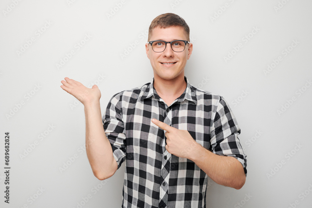 Handsome man in glasses holding something in hand, demonstrating empty space for product or text isolated on white studio background. Handsome man in glasses holding something in hand, demonstrating empty space for product or text isolated on white studio background.