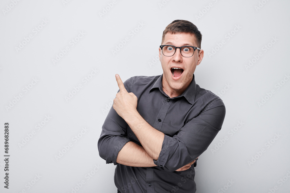 Handsome man in glasses pointing aside finger, demonstrating empty space for product or text isolated on white studio background. Handsome man in glasses pointing aside finger, demonstrating empty space for product or text isolated on white studio background.