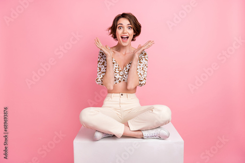 Full size photo of impressed astonished girl dressed trousers blouse sit on cube starinng at season sale isolated on pink color background