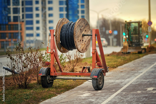 Wooden reel with fiber optic cable mounted on trailer for easy transportation. Laying optical fiber cable in new residential district. Cabling, laying of underground communications. Excavation works