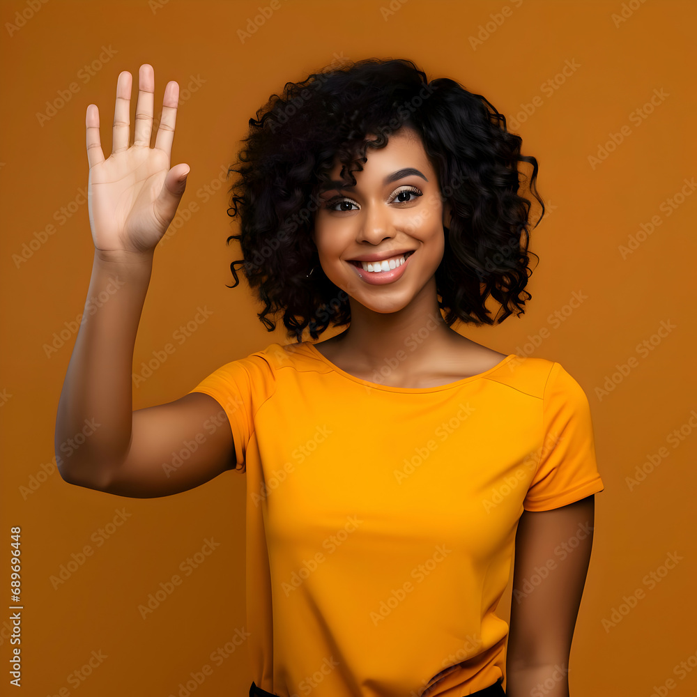 Photo of a dark skinned smiling woman waving on an orange background. High quality Photo of a dark skinned smiling woman waving on an orange background. High quality