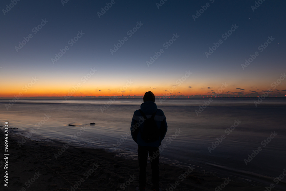Silhouette of a person looking at a beautiful twilight sky over the sea