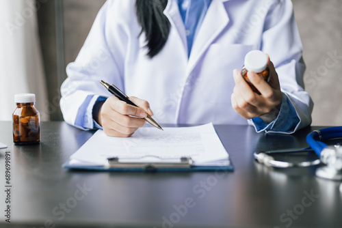 The doctor is writing a prescription. Doctor giving healthcare and medicine advice to patient in hospital examination room. photo