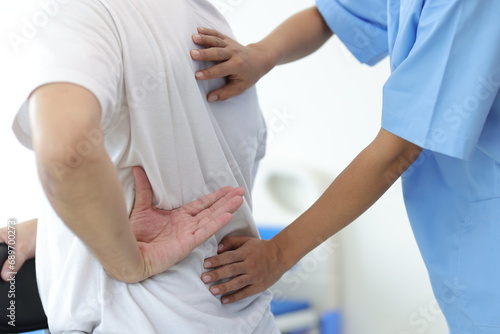 Doctor is diagnosing a male patient's back and lumbar pain in an examination room at a hospital. photo
