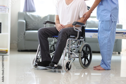 Doctor is inquiring about the condition of a patient with a leg injury in a hospital examination room. Nurse caring for the condition of a man in a wheelchair in a hospital.