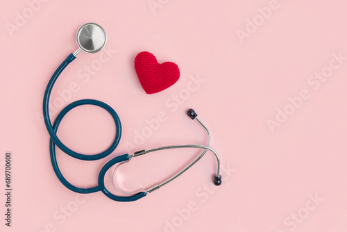 World Heart Day. Heart as a symbol of health, treatment, cardiology on a pink background with a medical statoscope. View from above. Global health concept. Listen to your heart
