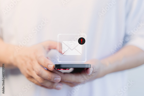 User hand using a mobile phone with an email icon, Email alert with a caution warning sign for notification error. Security protection on the internet, junk mail, and compromised information.