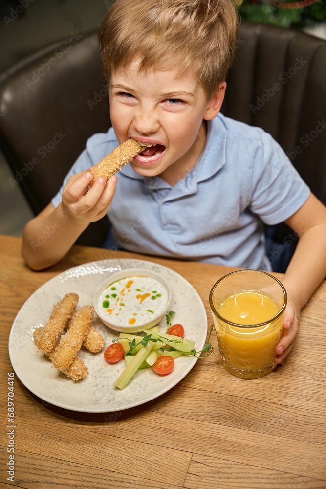 Hungry little boy eating fast food in restaurant on Christmas celebration Hungry little boy eating fast food in restaurant on Christmas celebration