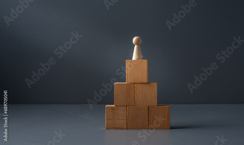 concept of being a winner ,wooden figure standing ontop of blocks , with a grey blue background . success in business , © robert