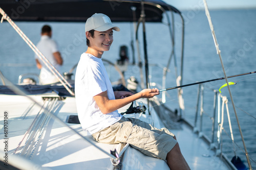 Smiling teen in a cap on a yacht